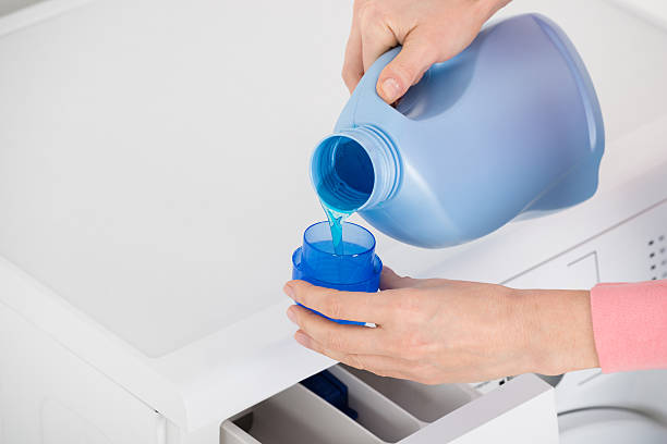 Close-up Of Female Hand Pouring Detergent In The Blue Bottle Cap LIQUID DETERGENT - Image 1