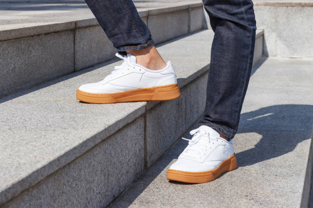 Male legs in jeans and white sneakers on the background of concrete stairs. SHOES COLLECTION6 - Image 1
